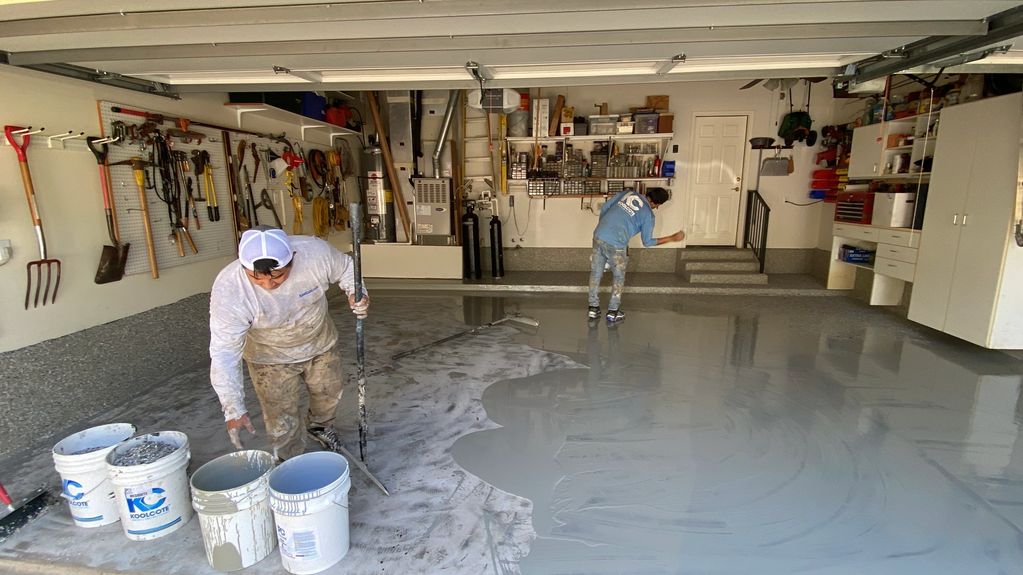 The polyurea base coat is squeegeed onto the garage floor and is followed by the flakes.