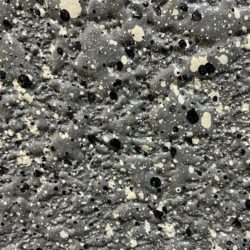 Textured surface with black and white paint splatters on a gray background.