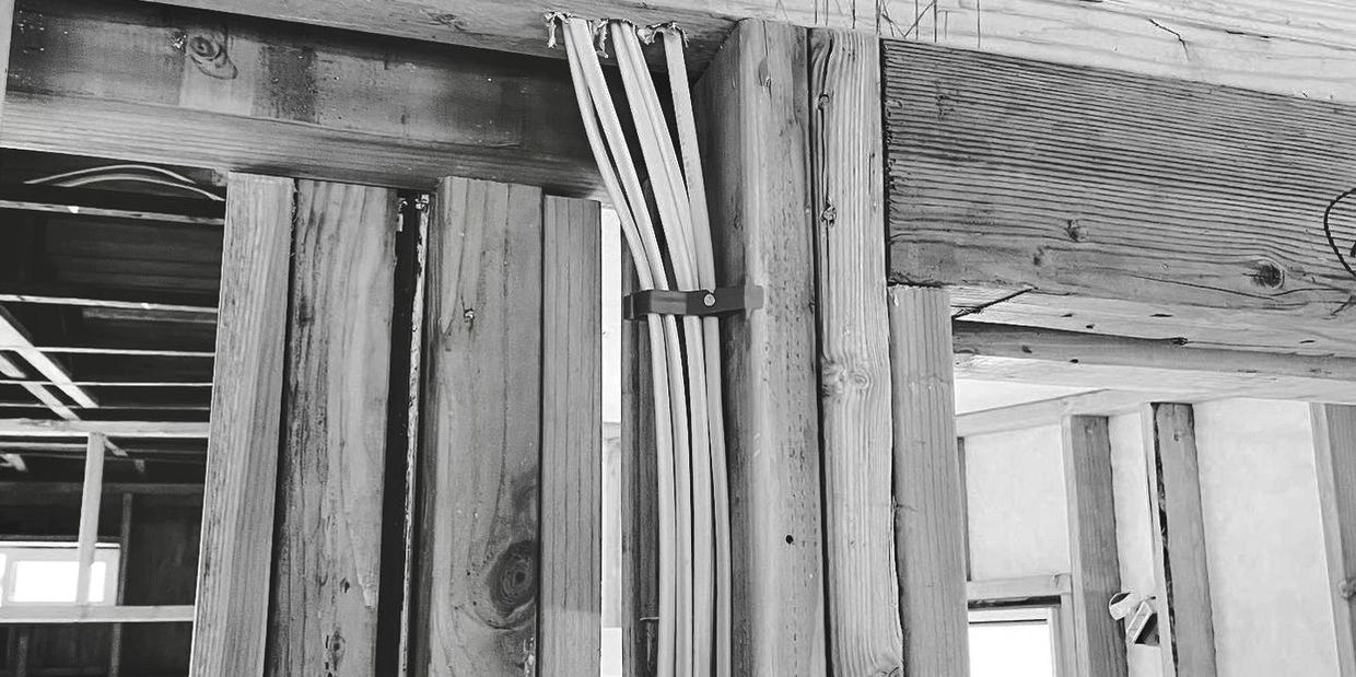 Electrical wiring inside wooden framing of a building under construction.
