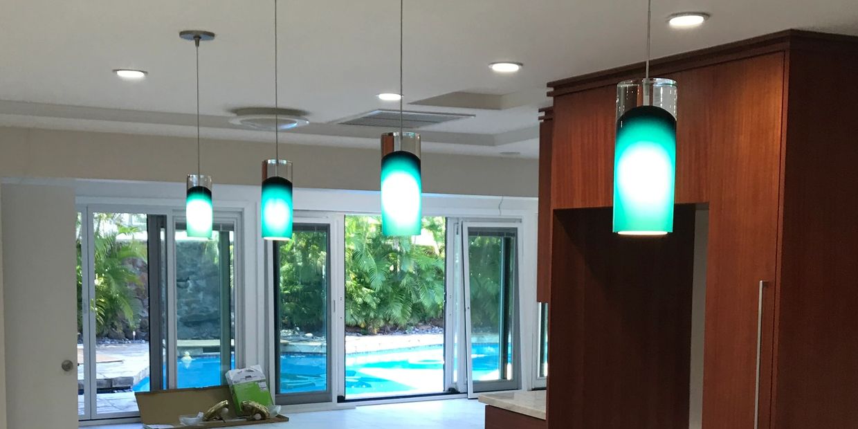 Modern kitchen lighting with a pool view through large windows.