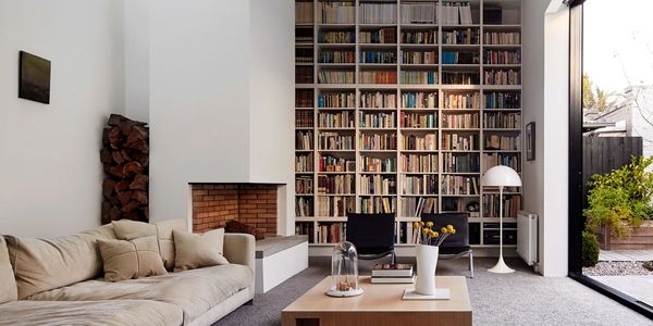 Modern living room with tall bookshelf, cozy sofa, and fireplace.