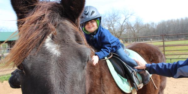 a little girl sitting on a horse while smiling