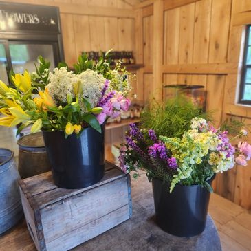 Two buckets of colorful flowers in a wooden room.