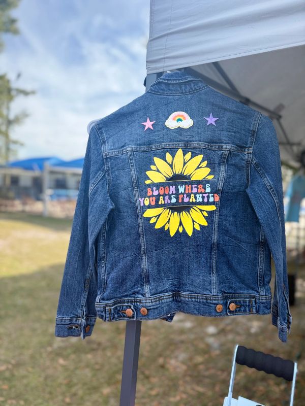 Denim jacket with colorful sunflower and uplifting message on the back.