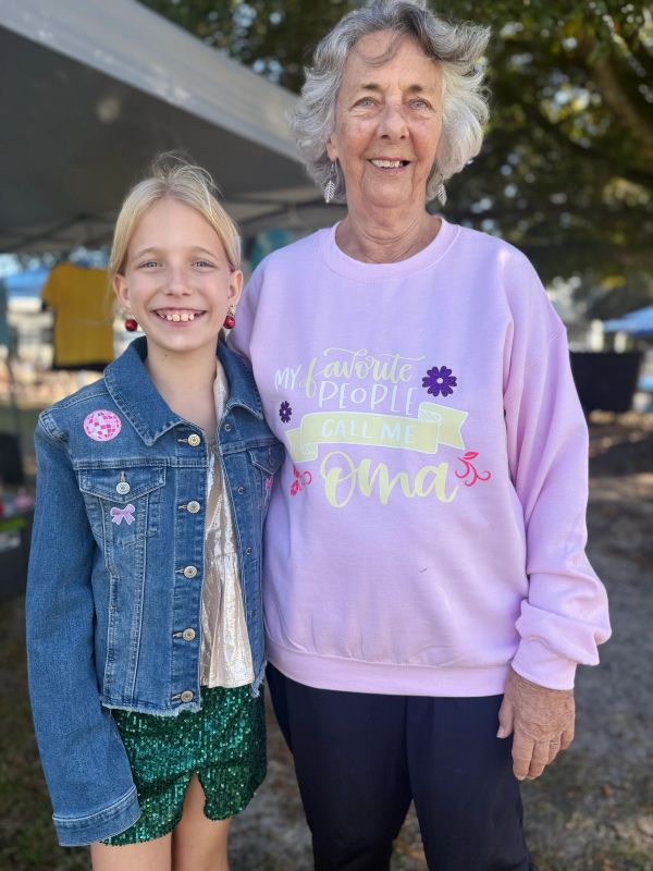 A smiling elderly woman and young girl posing together outdoors.