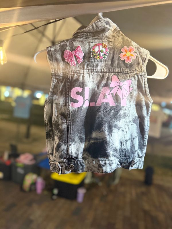Black and white sleeveless denim jacket with pink patches and 'S.L.A.Y' text.