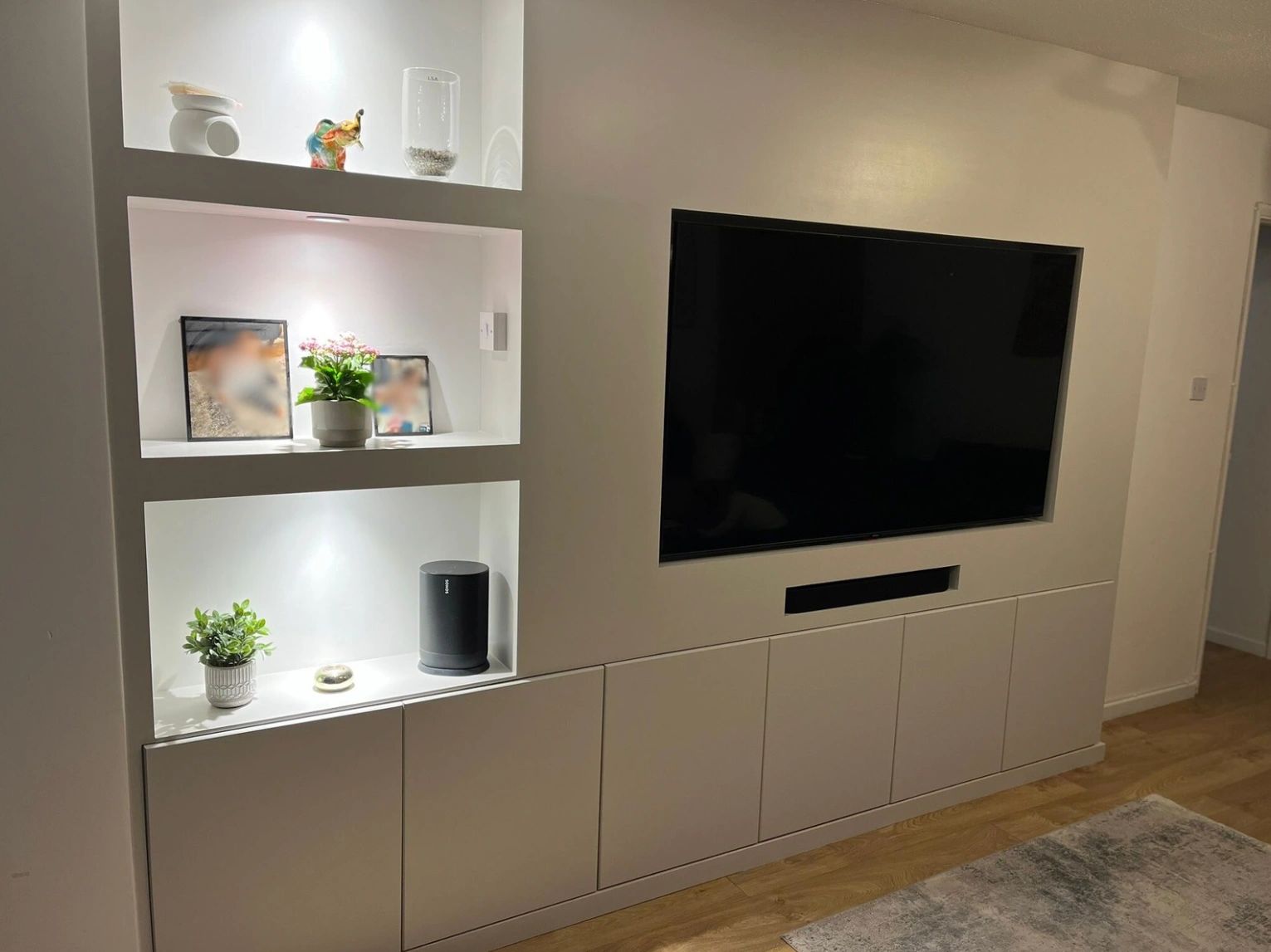 Modern built-in entertainment unit with TV and decorative shelves.