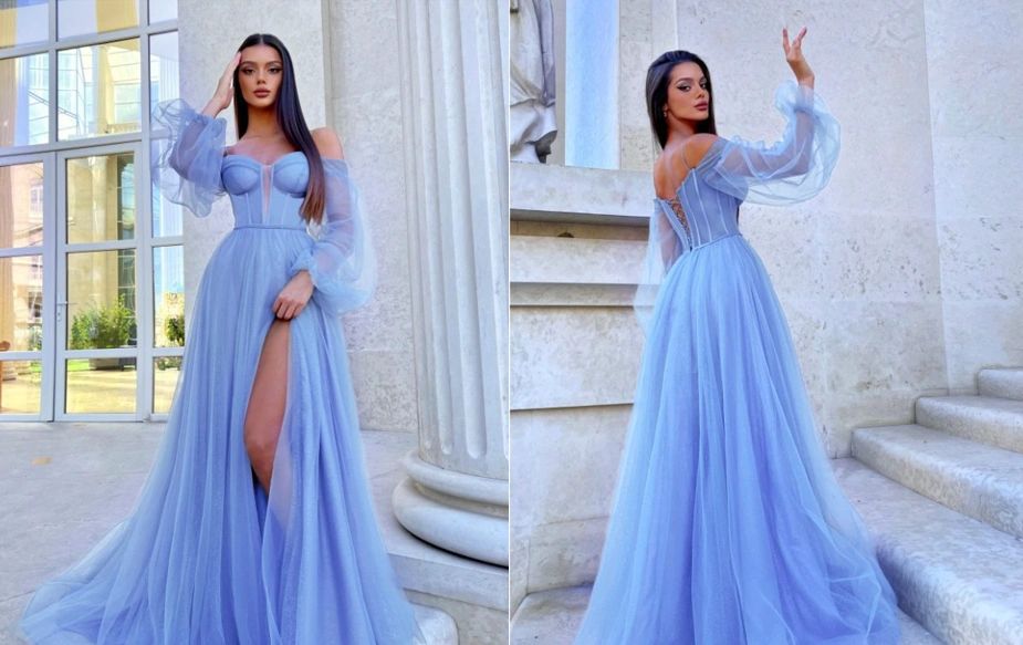 Woman in elegant light blue gown posing in front of classical architecture.