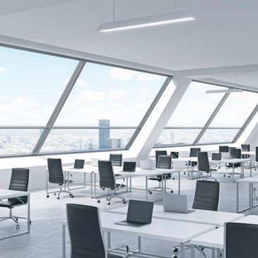 Modern office space with black chairs and laptops by large windows.