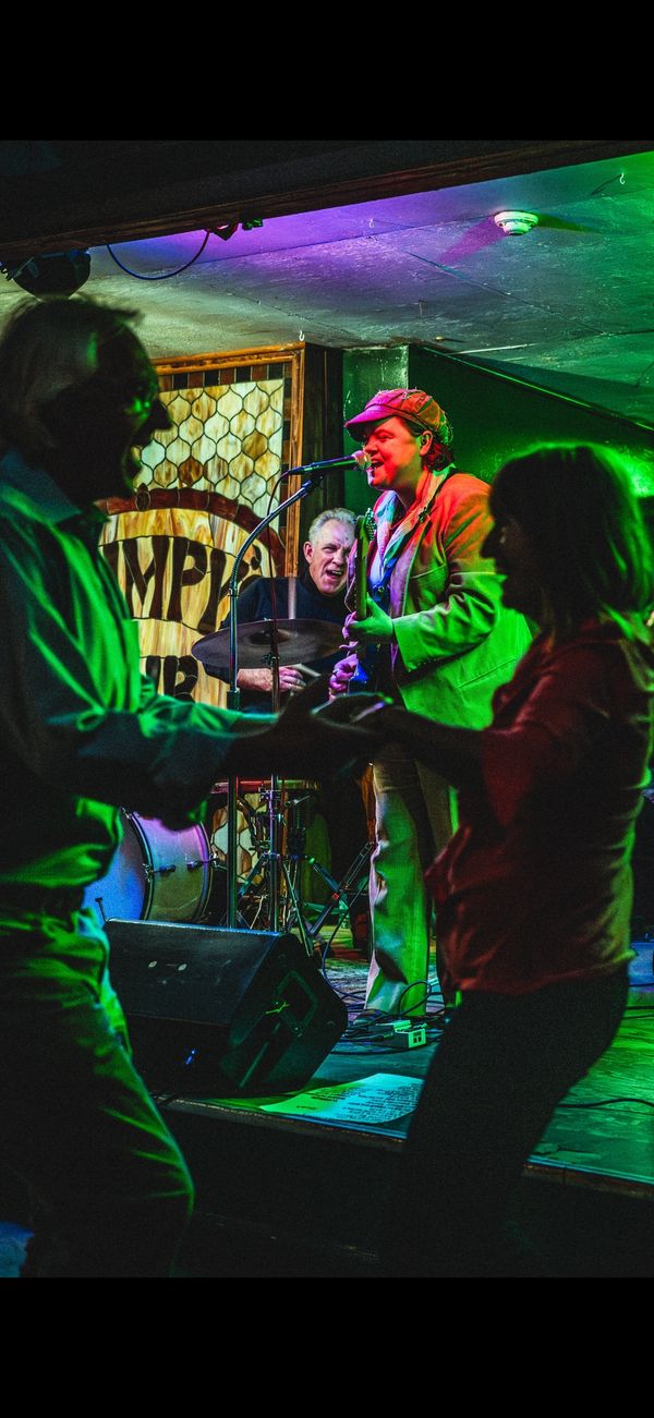 A vibrant live band with dancing audience in a cozy venue.