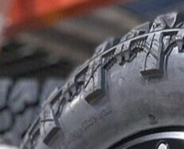 Stack of rugged off-road tires with detailed tread and alloy rims.