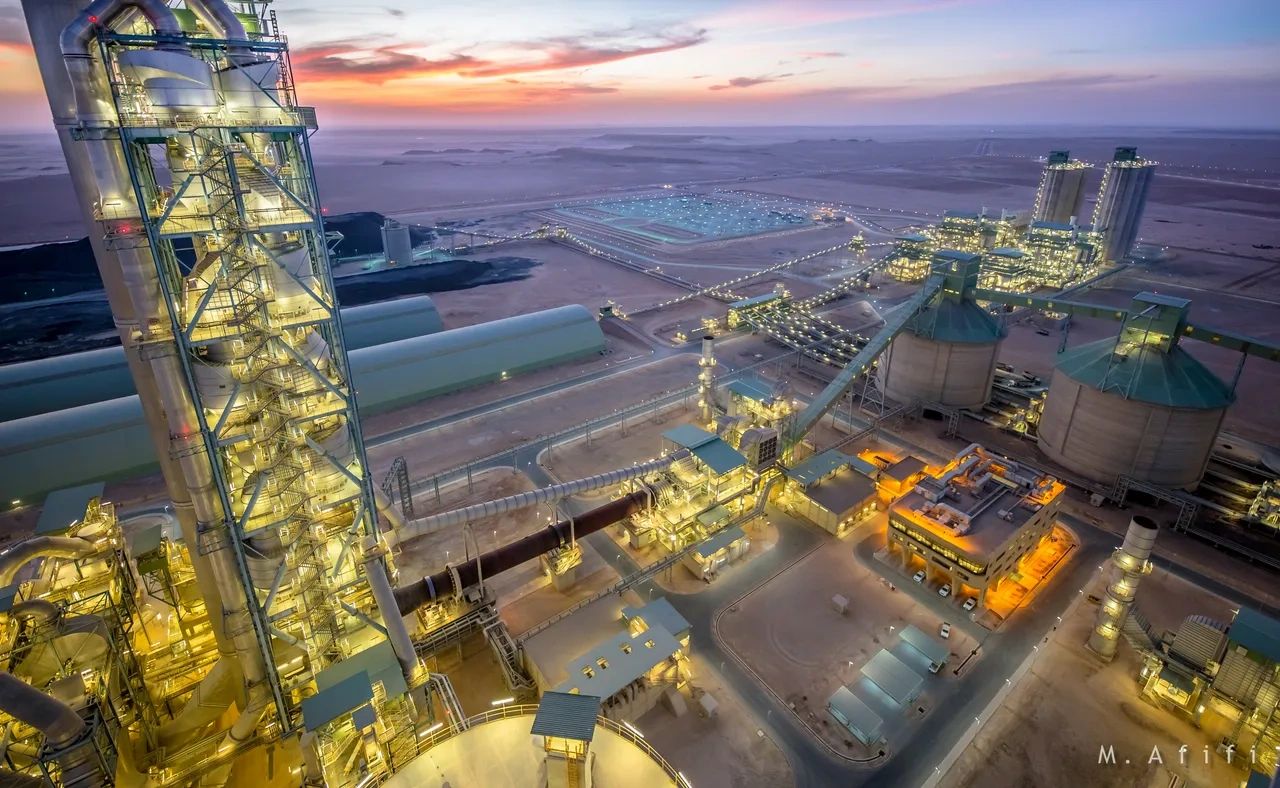 Sunset view of an illuminated industrial plant in a desert.