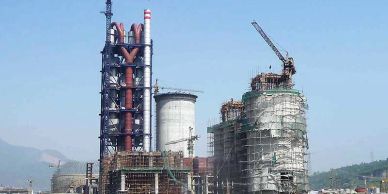 Industrial plant with cranes and scaffolding under clear sky.