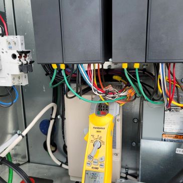 Electrical panel with colorful wires and a yellow Fluke device connected.
