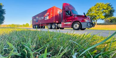 Red semi-truck driving on a sunny road.