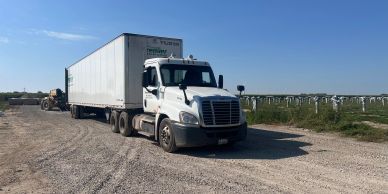 White semi-truck parked on a gravel road.