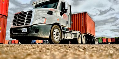 White semi-truck parked near shipping containers.