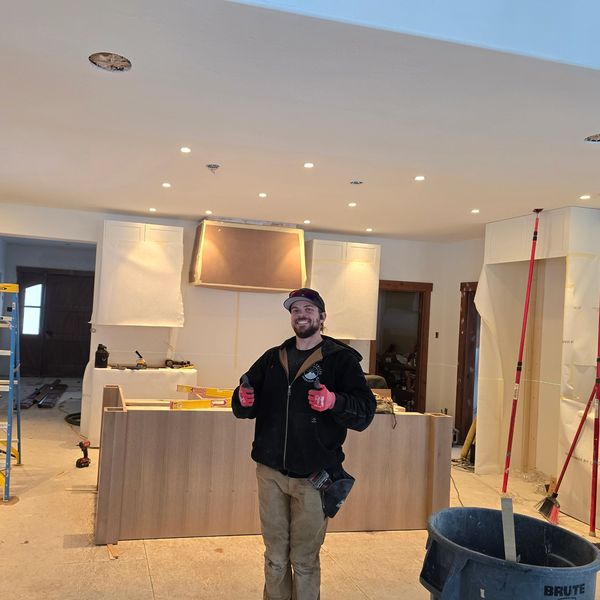 A man giving thumbs up in a kitchen under construction with tools and ladders around.
