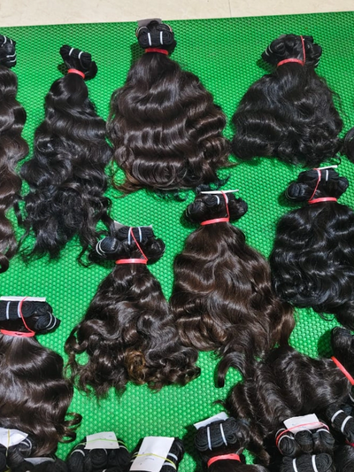 Bundles of wavy hair extensions arranged on a green mat.