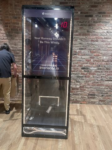 A wind tunnel machine with the message about runway windiness and Interlaced.io branding.