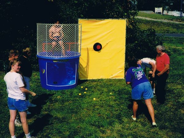 Group playing a dunk tank game outdoors on a sunny day.
