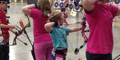Young archers aiming at targets indoors.