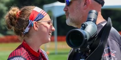Two people engaged in outdoor conversation with telescope.