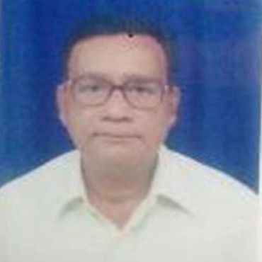 Portrait of a man wearing glasses and a white shirt against a blue background.