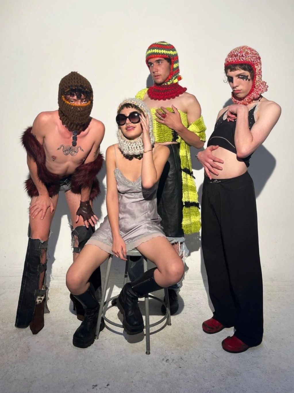 Four people in eclectic, avant-garde fashion with crochet balaclavas.