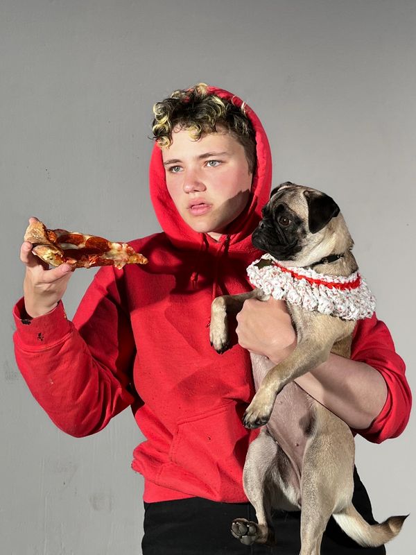 Young person in red hoodie holding a pug and a slice of pizza.
Photo taken by Nicky S. Garcia