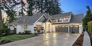 Modern suburban house with a spacious driveway at dusk.