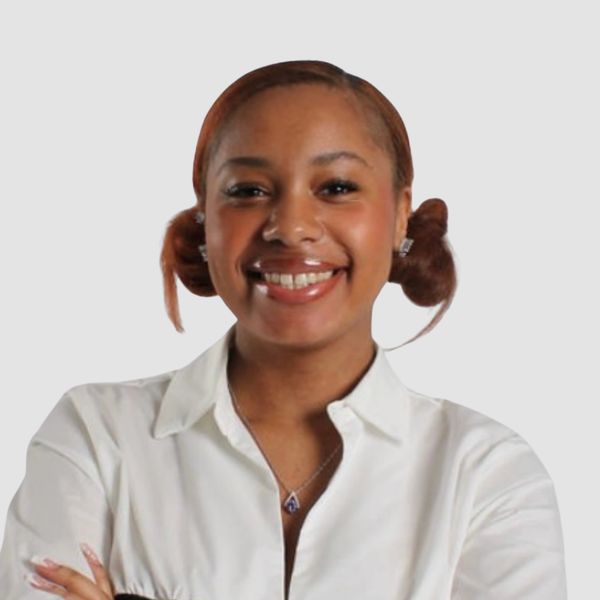 Smiling woman with styled hair wearing a white blouse.