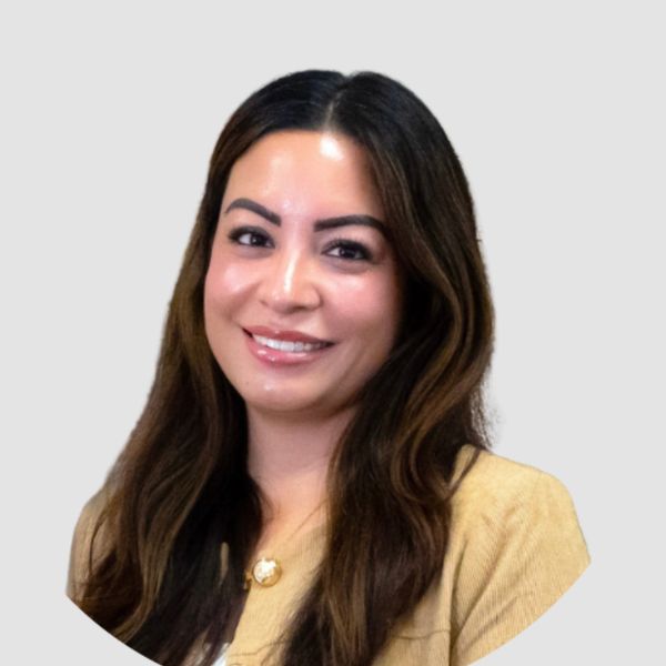 Smiling woman with long dark hair wearing a beige jacket.