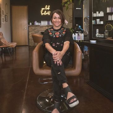 Woman sitting in a salon chair smiling.