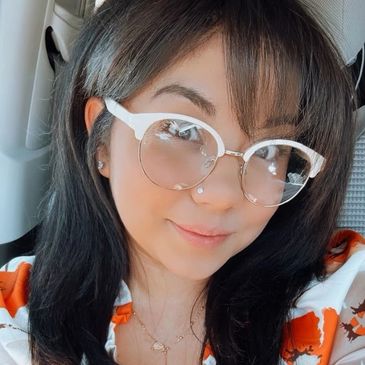 Young woman with glasses smiling inside a car.