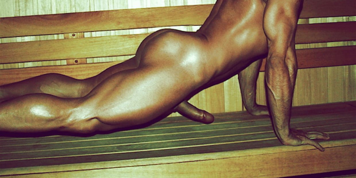 Naked man doing push-up on wooden bench.