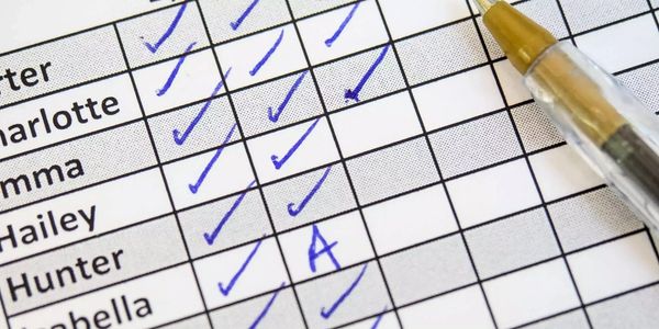 A checklist with names and blue pen checkmarks and an 'A' grade.