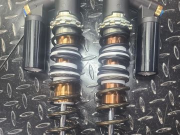 Pair of metal coil shock absorbers on a textured metal surface.
