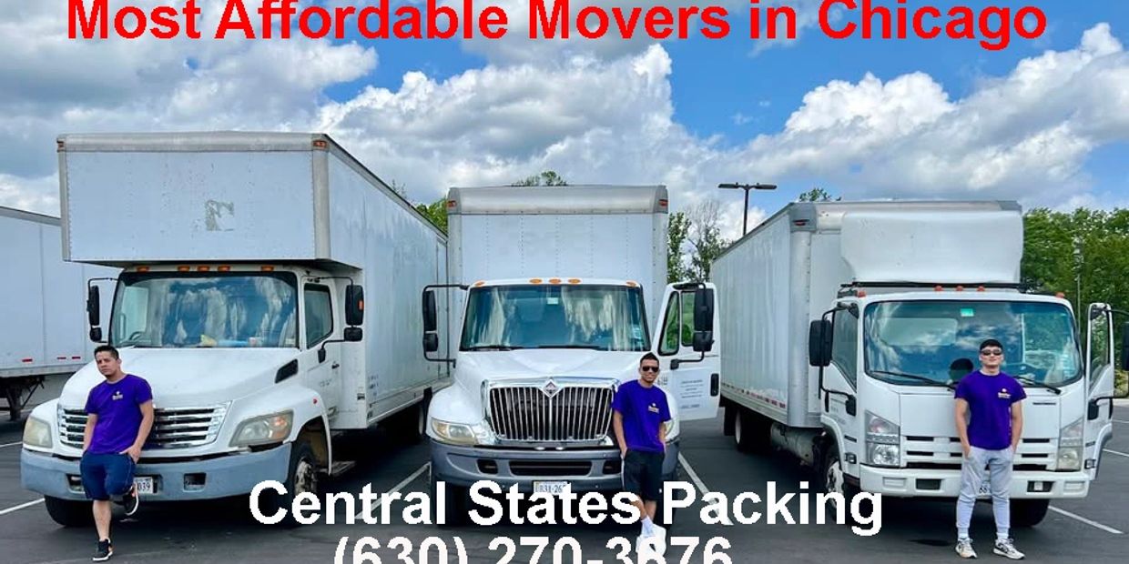 Three movers in purple shirts stand by white moving trucks in a parking lot.