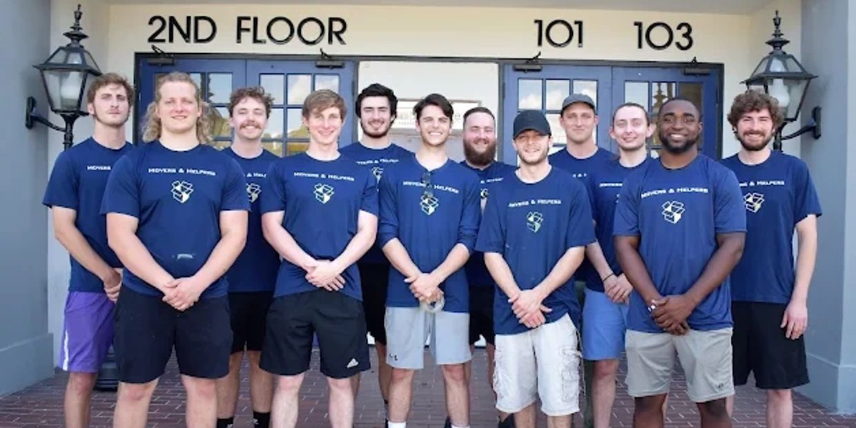 Group of young men wearing matching blue shirts posing outside a building.