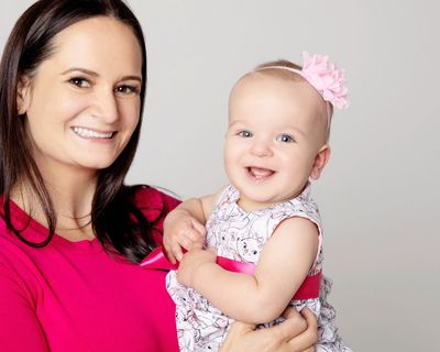 Solo mother by choice holding her young donor-conceived daughter smiling at the camera.