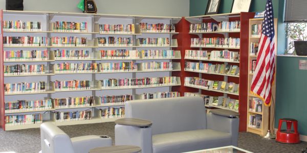 Modern library corner with shelves, American flag, and seating.