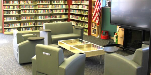 Modern library seating area with armchairs and a TV.