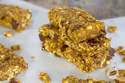 Stack of three homemade granola bars on parchment paper.