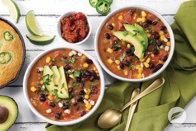 Two bowls of colorful vegetarian chili garnished with avocado slices and cilantro.