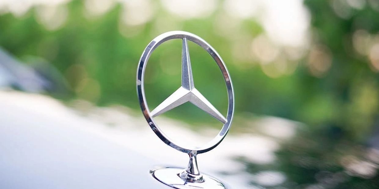 Close-up of a Mercedes-Benz hood ornament on a car.