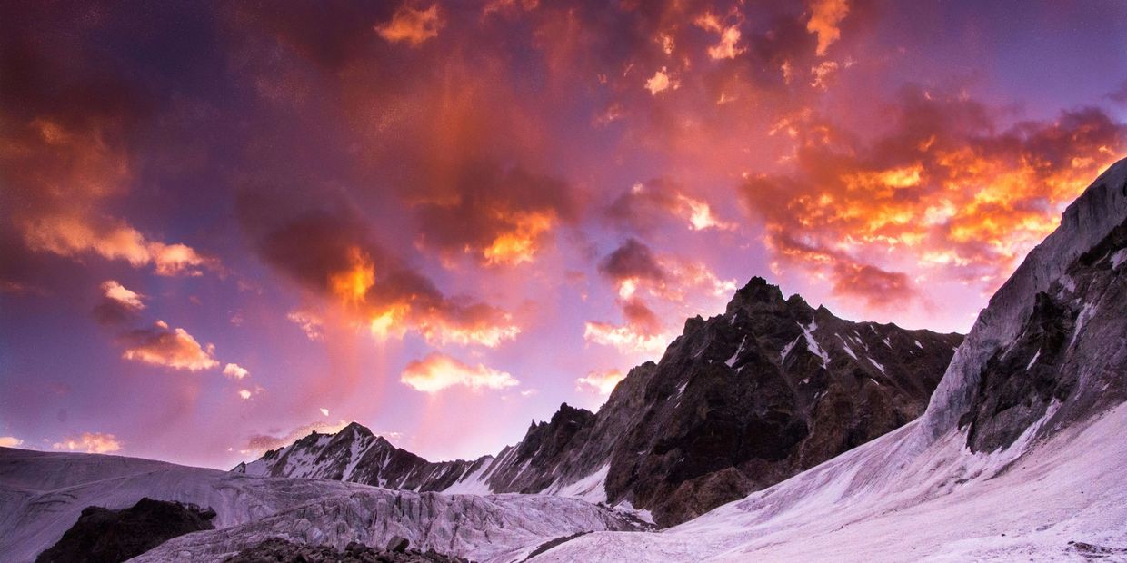 Snowy mountains under a vibrant purple and orange sunset sky.