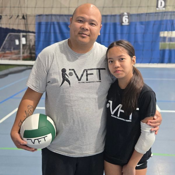 Two volleyball players posing in a gym.