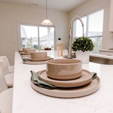Modern kitchen island with beige dinnerware and green napkins.