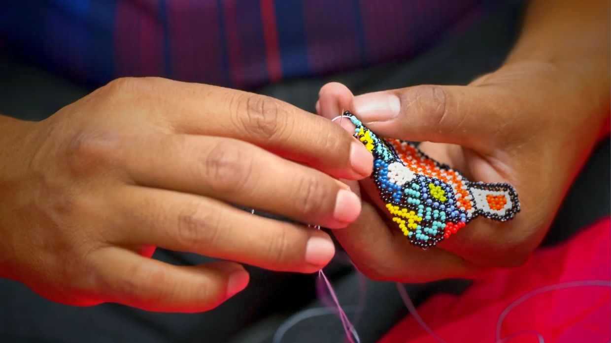 Hands weaving colorful beadwork with intricate patterns.
